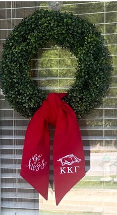 a wreath with the words go hogs and a red bow hanging on a window sill