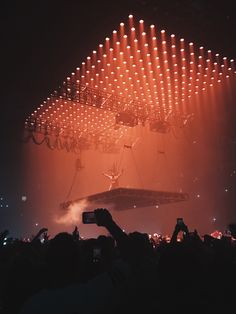 a large group of people at a concert with their cell phones up in the air