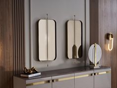 two mirrors on the wall next to a cabinet with gold trimmings and lights