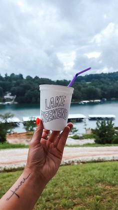 a person holding up a cup with a purple straw in it's mouth and the words lake weekend written on it