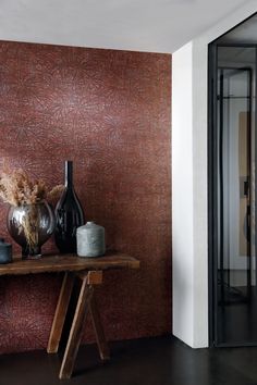 two vases are sitting on a table in front of a wallpapered background