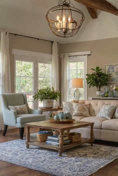 a living room filled with furniture and a chandelier hanging from the ceiling in front of two windows