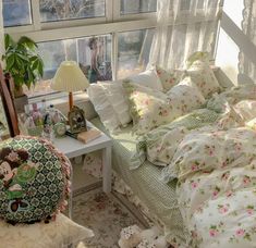 a bed with floral sheets and pillows in a bedroom next to a window that looks out onto the yard