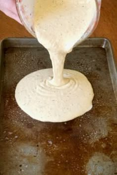 a person pouring batter into a pan on top of a table