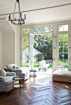 a living room filled with lots of furniture next to a large open doored window