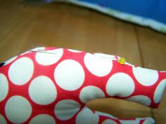 a red and white polka dot stuffed animal sitting on top of a wooden floor next to a pair of scissors