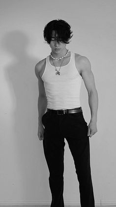 black and white photograph of a young man with his hands on his hips, standing in front of a wall