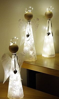 three lighted angel figurines sitting on top of a wooden table