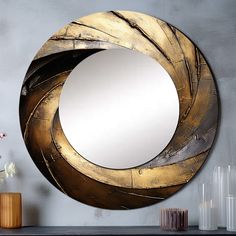 a round mirror sitting on top of a table next to a vase with flowers in it