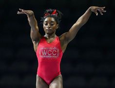 a woman standing on top of a balance beam in a red leor leor leor