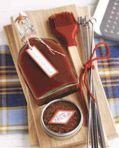 a wooden tray topped with lots of cooking utensils next to a bottle of sauce