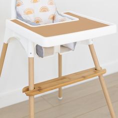 a baby's highchair with a cushion on the seat and wooden legs