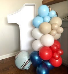 a number one balloon column with baseballs and balloons on the floor next to it