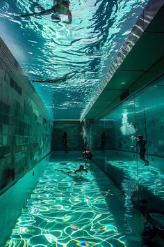 people are swimming in an indoor pool surrounded by tile walls and flooring, while the water is reflecting sunlight