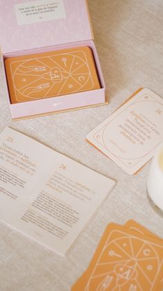 an orange and pink box sitting on top of a table next to some paper cards