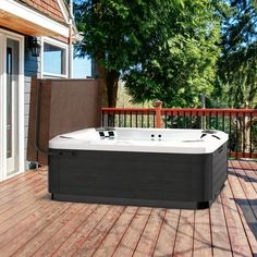 a hot tub sitting on top of a wooden deck next to a building and trees