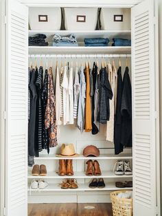 an open closet with clothes and shoes hanging on the shelves, along with white shutters