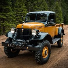 an old yellow truck driving down a dirt road