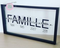 a family name sign is displayed in a black frame on a wooden table with a white wall behind it