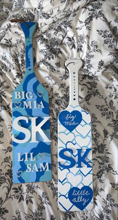 two wooden tags on a bed with blue and white designs