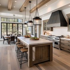 a large kitchen with an island, stove and dining table in the center is surrounded by wood flooring