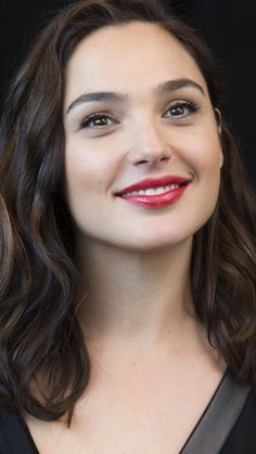 a close up of a person wearing a black shirt and red lipstick with long wavy hair