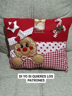 a red pillow with a gingerbread man on it sitting on a couch next to a christmas tree