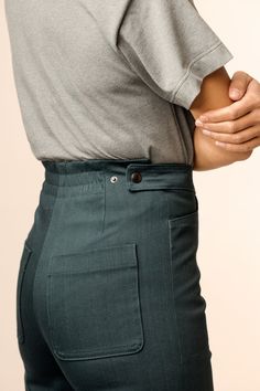 a person in grey shirt and green pants with their hands on the back of his waist