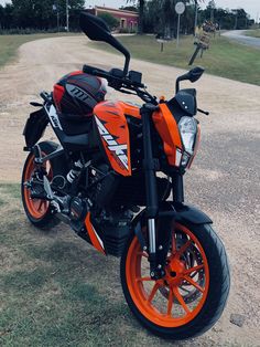 an orange and black motorcycle parked in the dirt