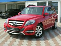 a red mercedes suv parked in front of a building