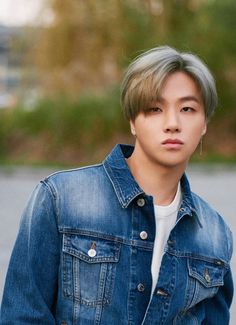 a young man wearing a denim jacket and white t - shirt looks at the camera