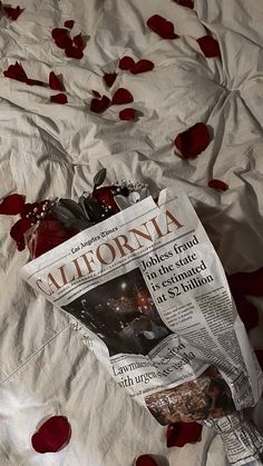 a newspaper laying on top of a bed covered in rose petals and petals scattered around it