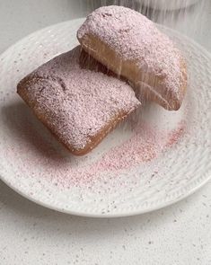 two powdered donuts on a white plate