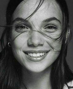 a black and white photo of a woman with her hair blowing in the wind, smiling