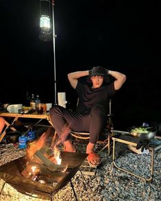 a man sitting on top of a chair next to a fire pit