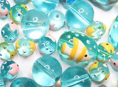 many different colored glass beads on a white surface with blue and yellow designs around them