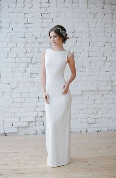 a woman standing in front of a brick wall wearing a white dress and headpiece