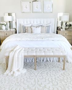 a white bed sitting in a bedroom next to two framed pictures