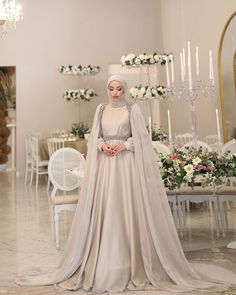 a woman in a wedding dress standing next to a table with flowers and candles on it