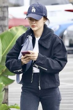 a woman in black jacket and hat holding a cell phone