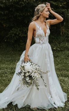 a woman in a white wedding dress holding a bouquet and posing for the camera with her hand on her head