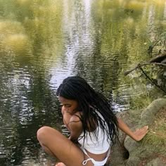 a woman sitting on the edge of a body of water