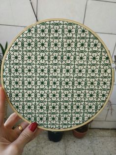 a person holding up a green and white plate with an intricate design on the front