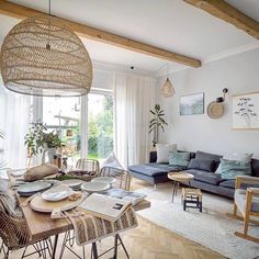 a living room filled with furniture and a wooden table in front of a large window