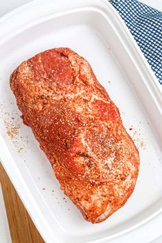 a piece of meat in a white tray on top of a blue and white towel