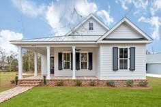 a white house with black shutters on the front porch and brick steps leading up to it