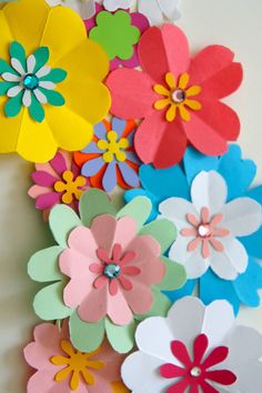 colorful paper flowers are arranged on the wall