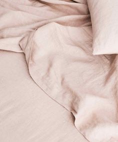 an unmade bed with pink sheets and pillows