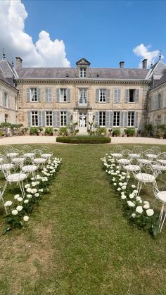 rows of white chairs in front of a large building with lots of windows and doors