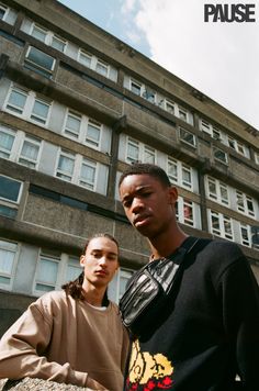 two young men standing in front of a tall building with the words pause on it